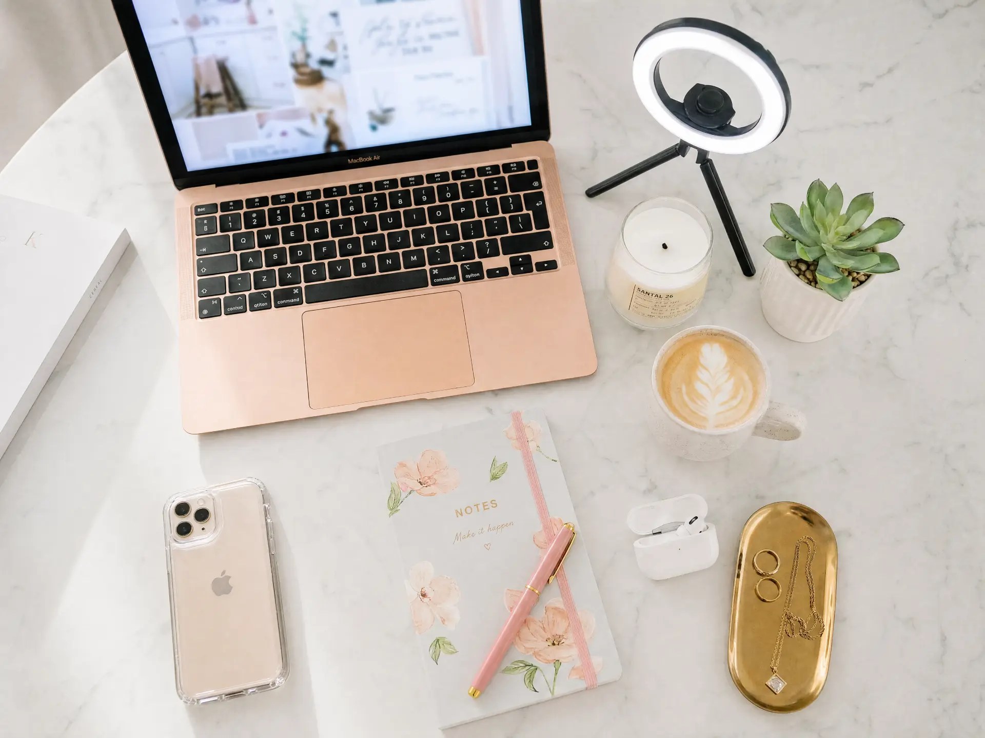Minimal desk with a laptop, ring light and small plant in warm lamp light