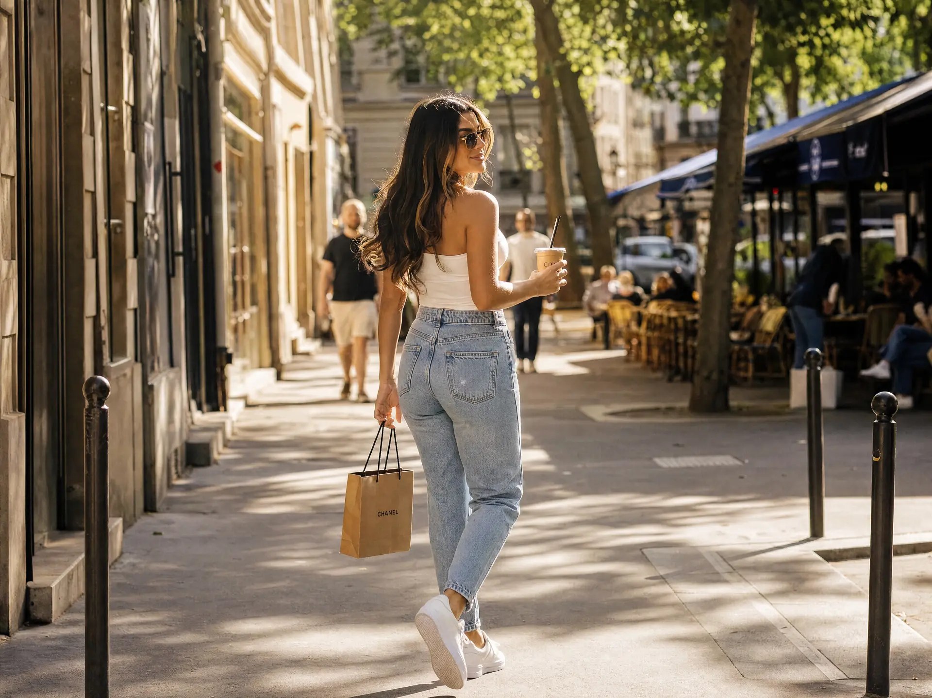 Young woman walking a sunlit city street with a coffee
